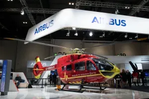 Maac Red Helicopter On Display In A Large Building With People Standing Around
