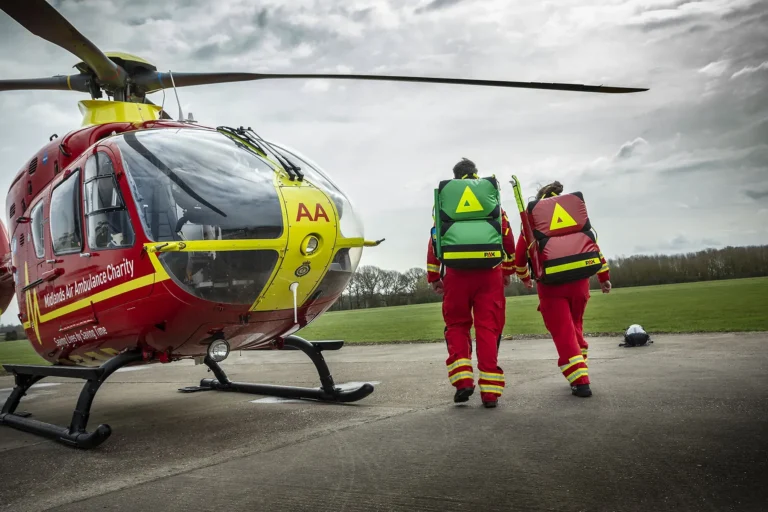 Maac Rescue Personnel Walking Towards A Helicopter On A Runway