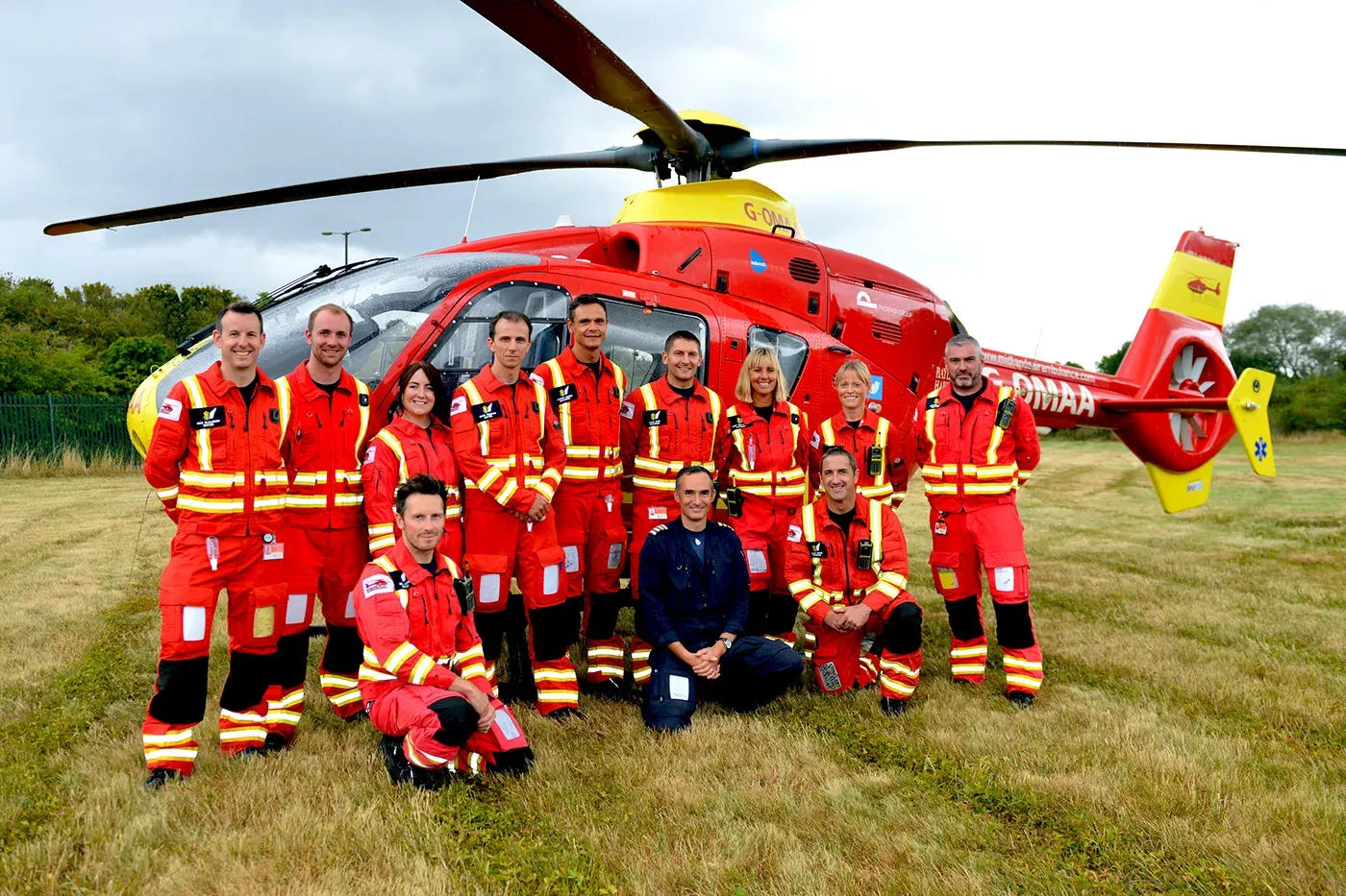 Maac Rescue Team Posing In Front Of A Helicopter In A Field