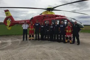 Maac Rescue Team Standing In Front Of A Helicopter On A Runway
