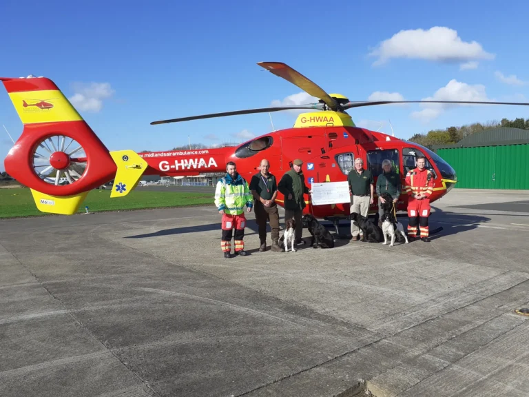 Maac Rescue Team Standing In Front Of A Helicopter On A Runway