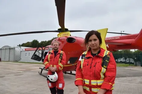 Maac Rescue Team Standing In Front Of A Helicopter On A Tarmac