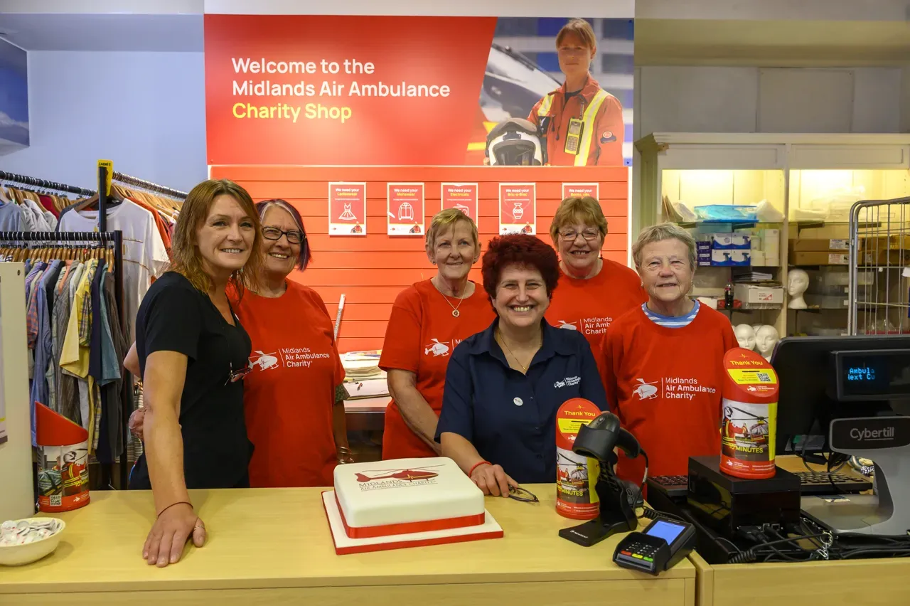 Maac Several People In Red Shirts Standing Behind A Counter With A Cake