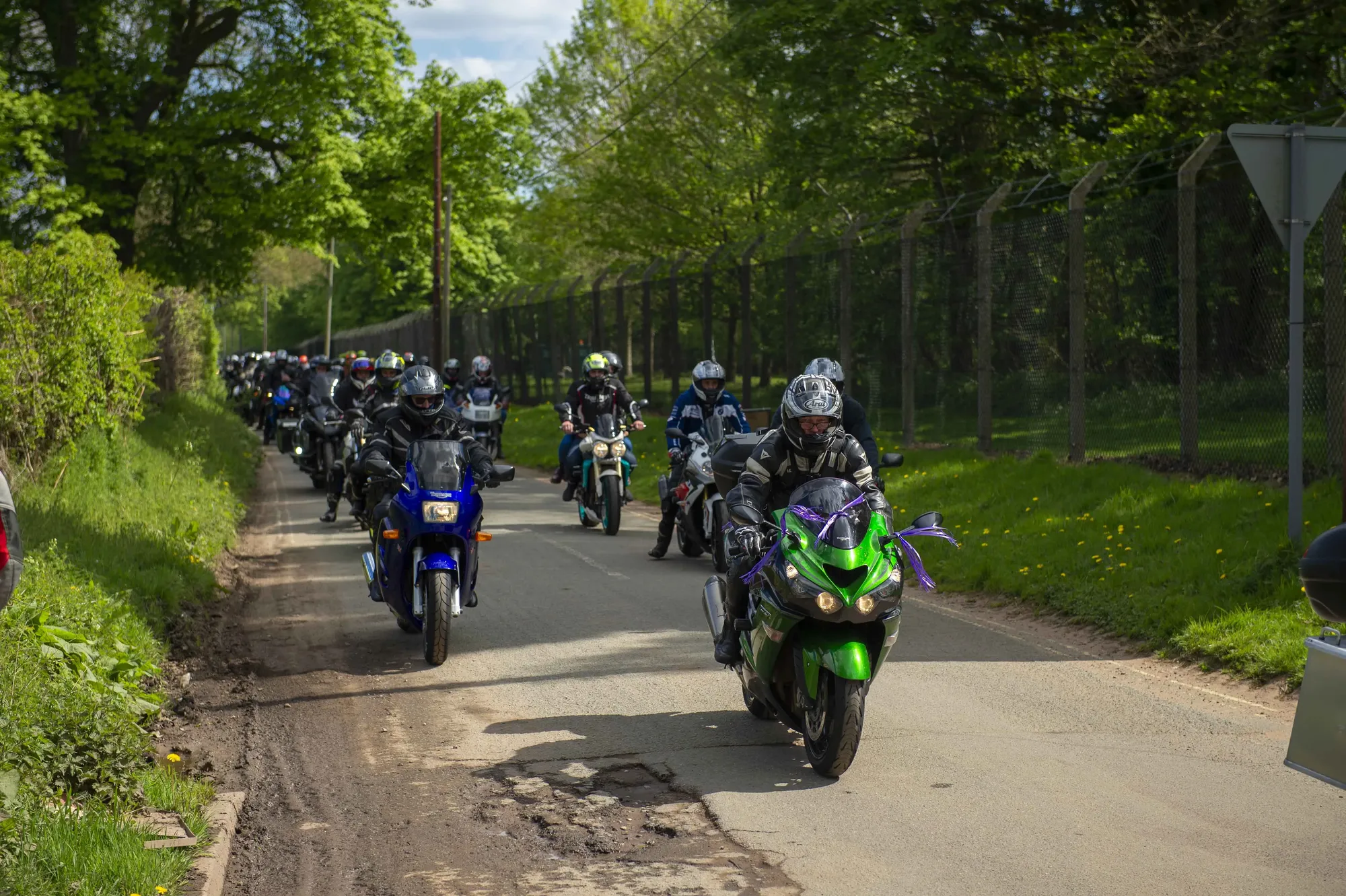 Maac Several People On Motorcycles Are Riding Down A Road In A Line
