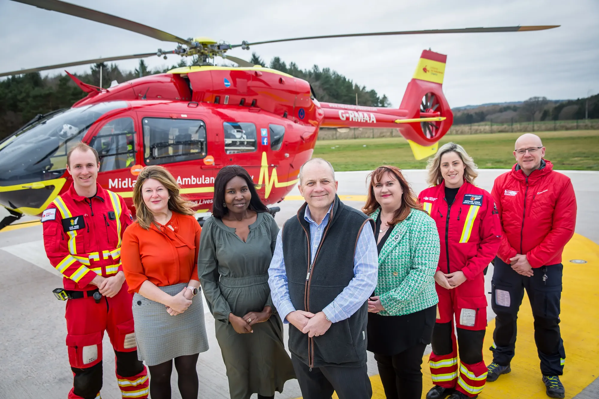 Maac Several People Standing In Front Of A Helicopter On A Runway