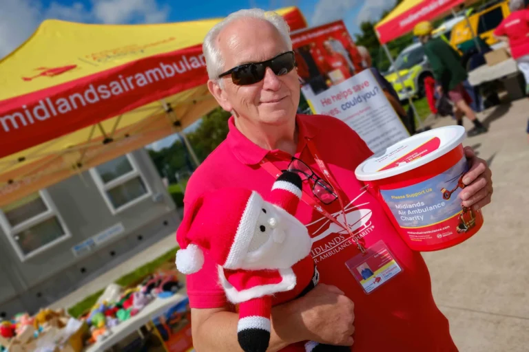 Maac Smiling Man In Red Shirt Holding A Bucket Of Food And A Stuffed Animal