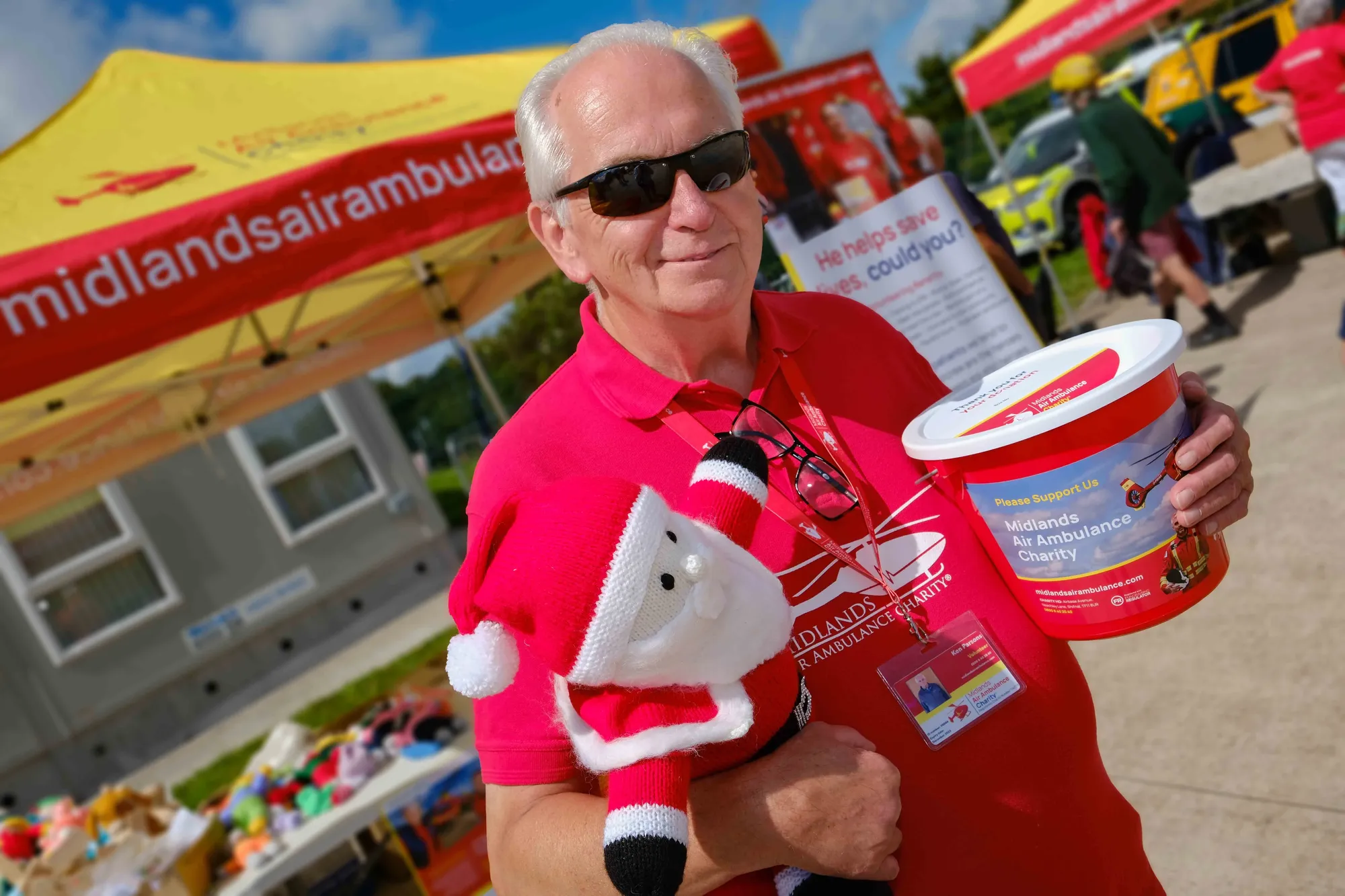 Maac Smiling Man In Red Shirt Holding A Bucket Of Food And A Stuffed Animal