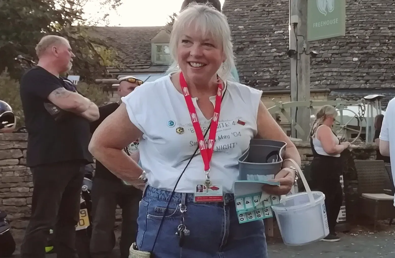 Maac Smiling Woman In A White Shirt And Blue Skirt Holding A Bucket