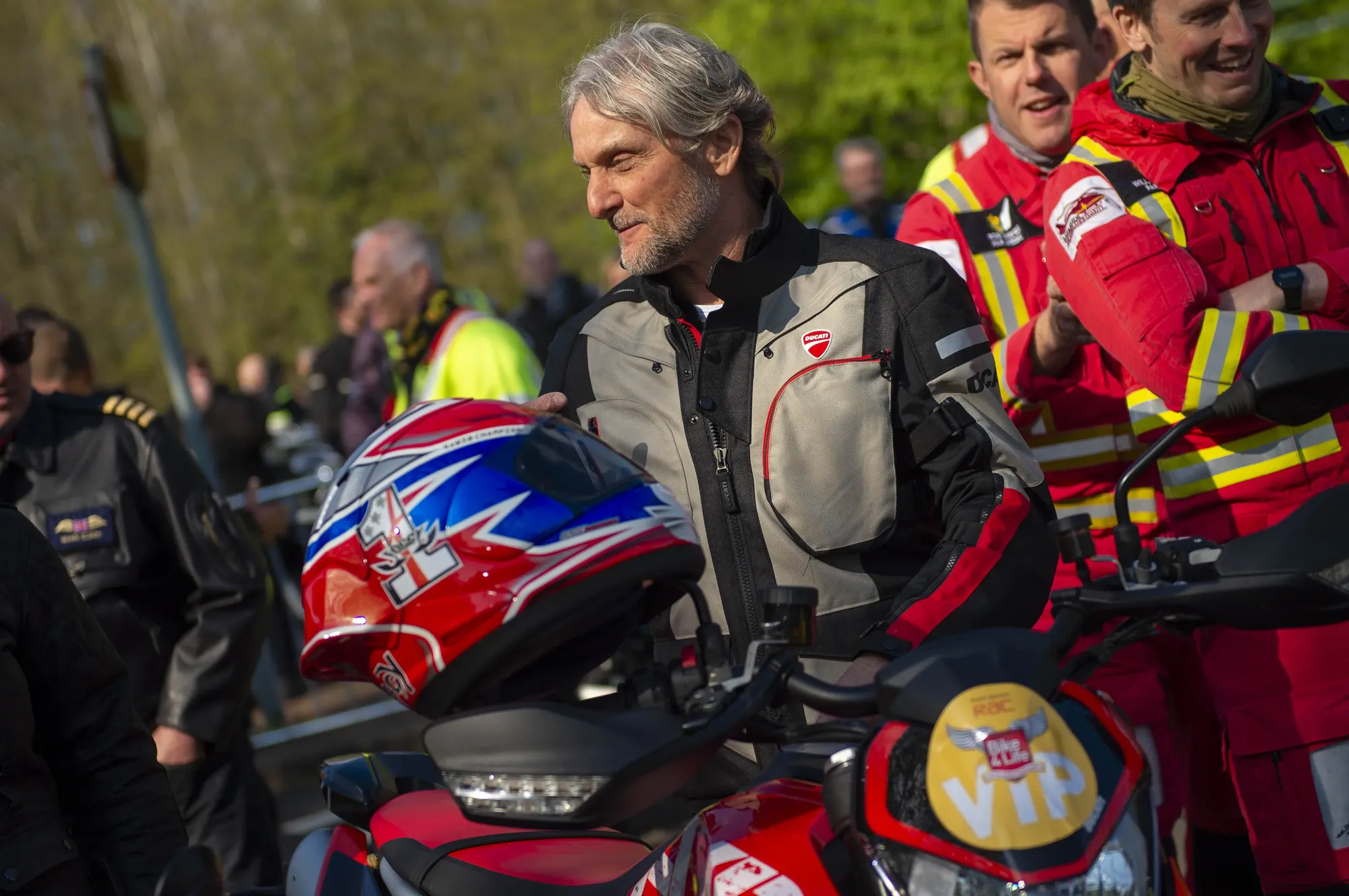 Maac There Are Many People Standing Around A Motorcycle With A Helmet On