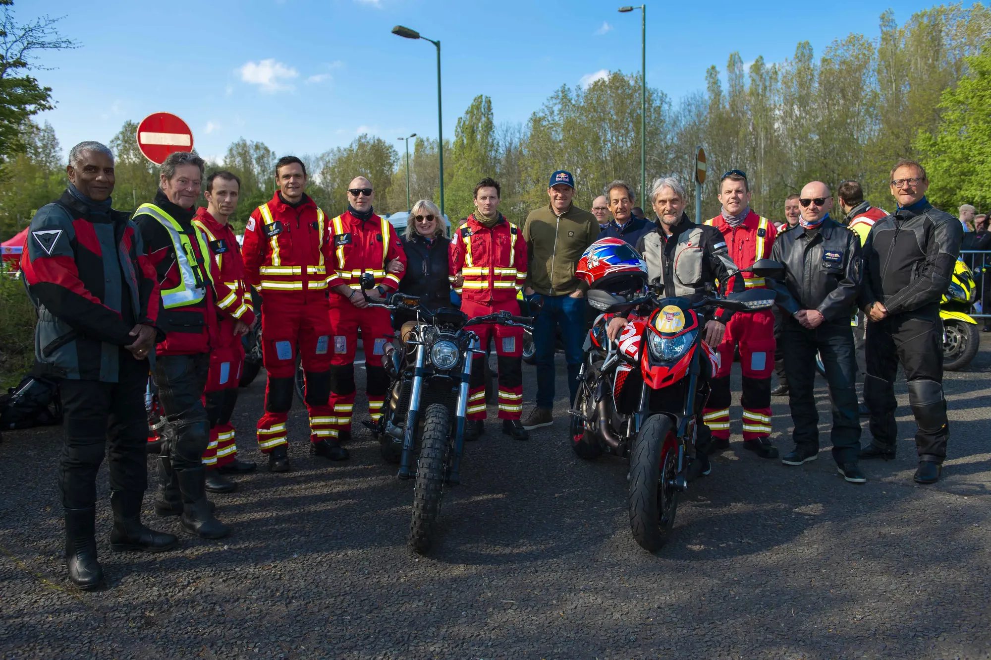 Maac There Are Many People Standing Around A Motorcycle With A Number Of Them