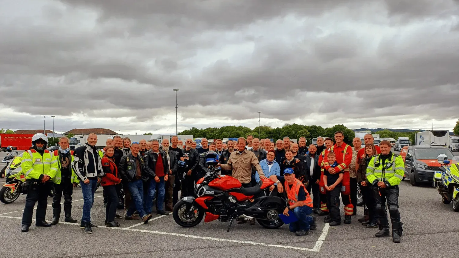 Maac There Are Many People Standing In A Parking Lot With Motorcycles