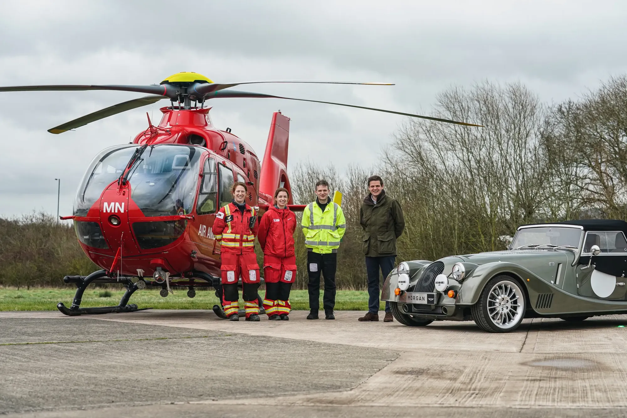 Maac There Are People Standing Next To A Helicopter And A Car