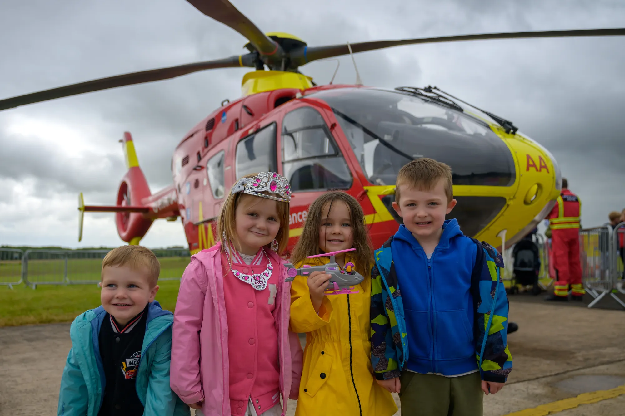 Maac There Are Three Children Standing In Front Of A Helicopter On The Tarmac