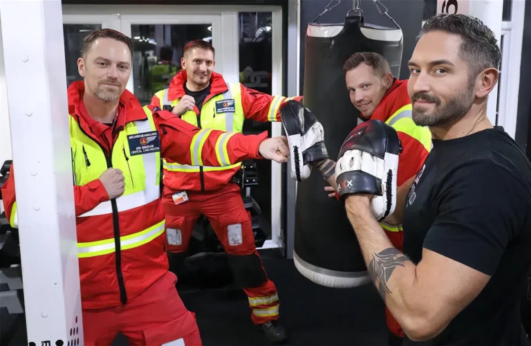 Maac There Are Three Men In Red And Yellow Uniforms Working On A Punching Bag