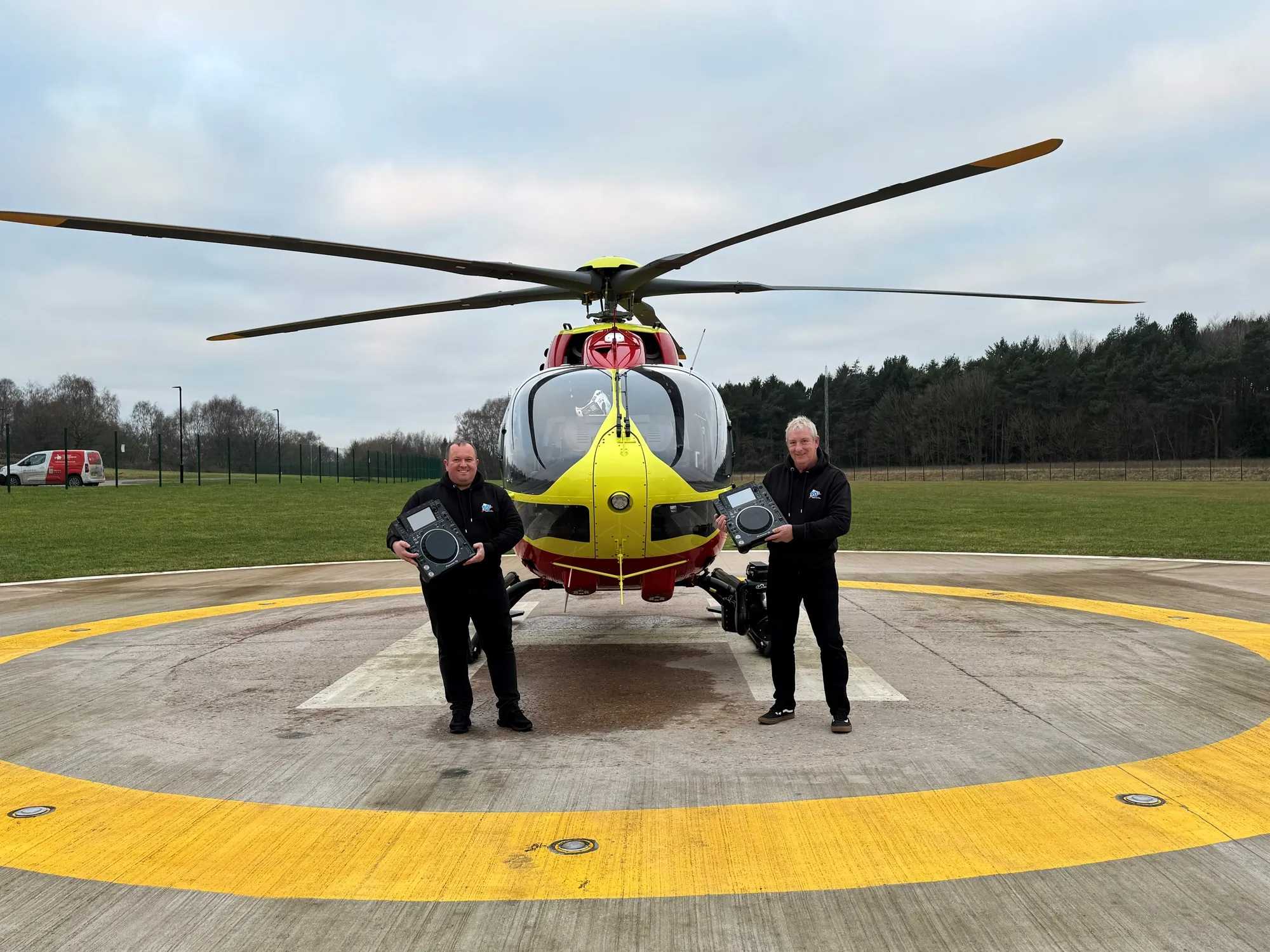 Maac There Are Two Men Standing Next To A Helicopter On The Runway