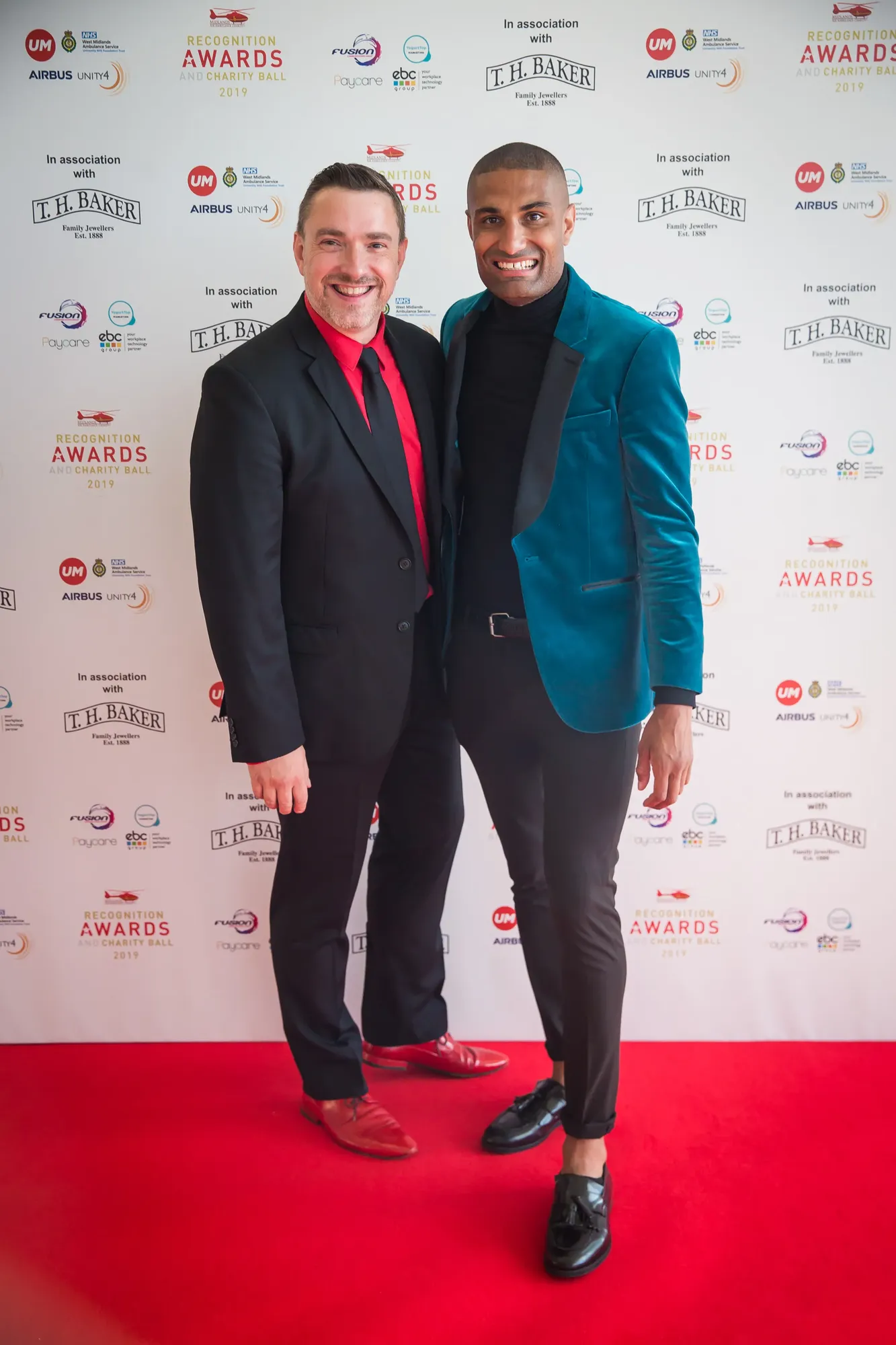 Maac There Are Two Men Standing On A Red Carpet Together
