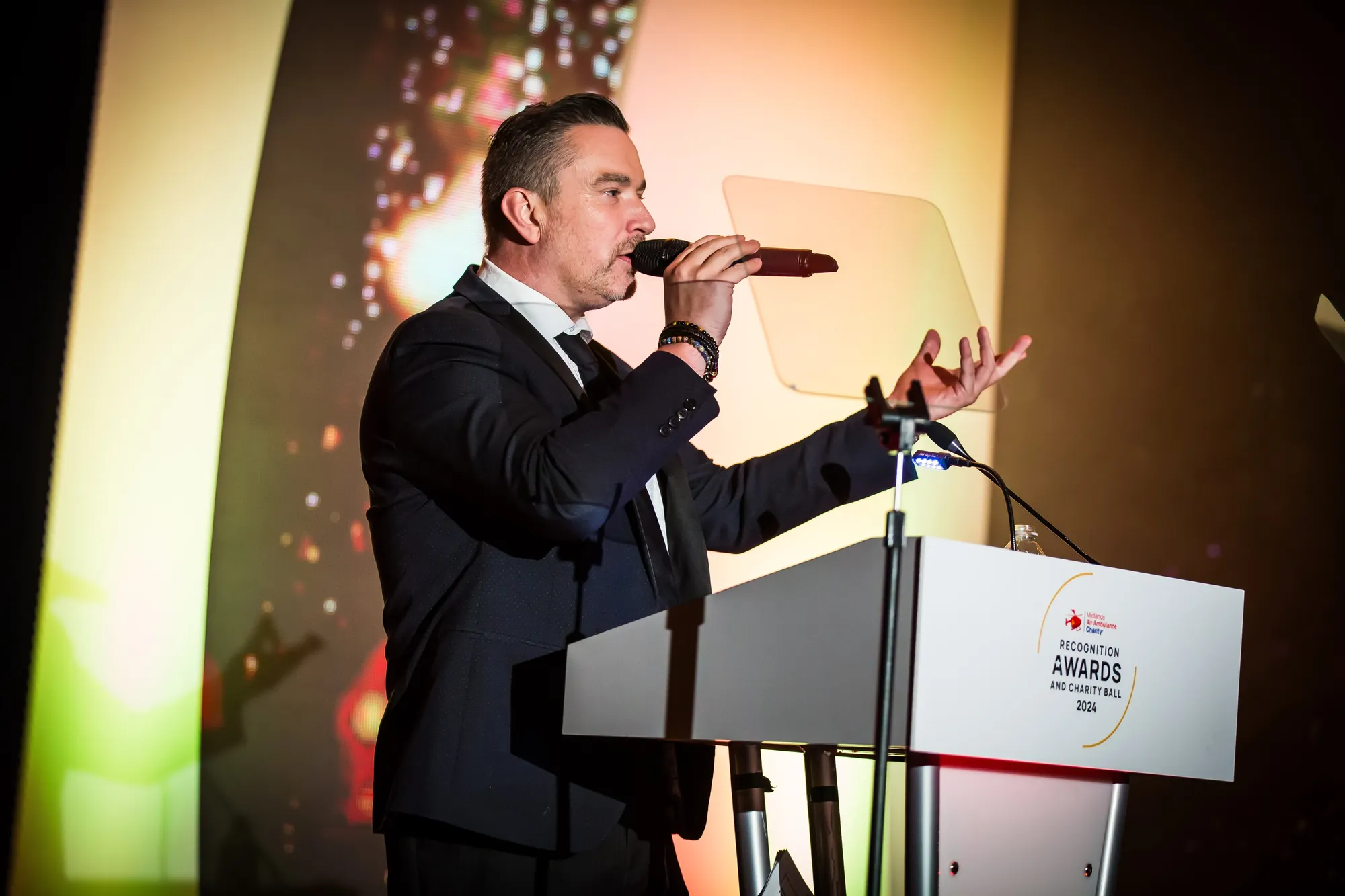 Maac There Is A Man In A Suit Speaking Into A Microphone