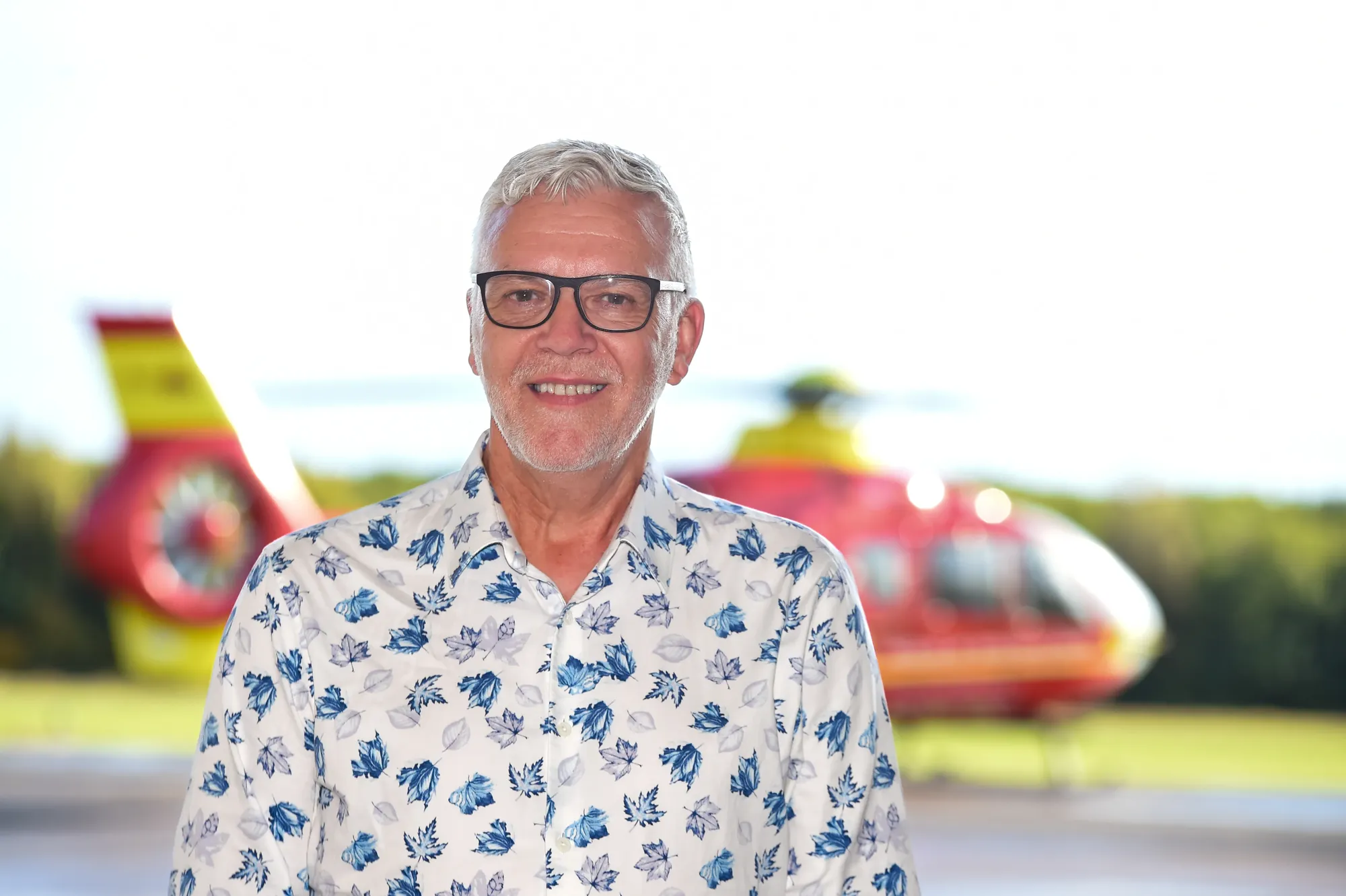 Maac There Is A Man Standing In Front Of A Helicopter With A Helicopter In The Background