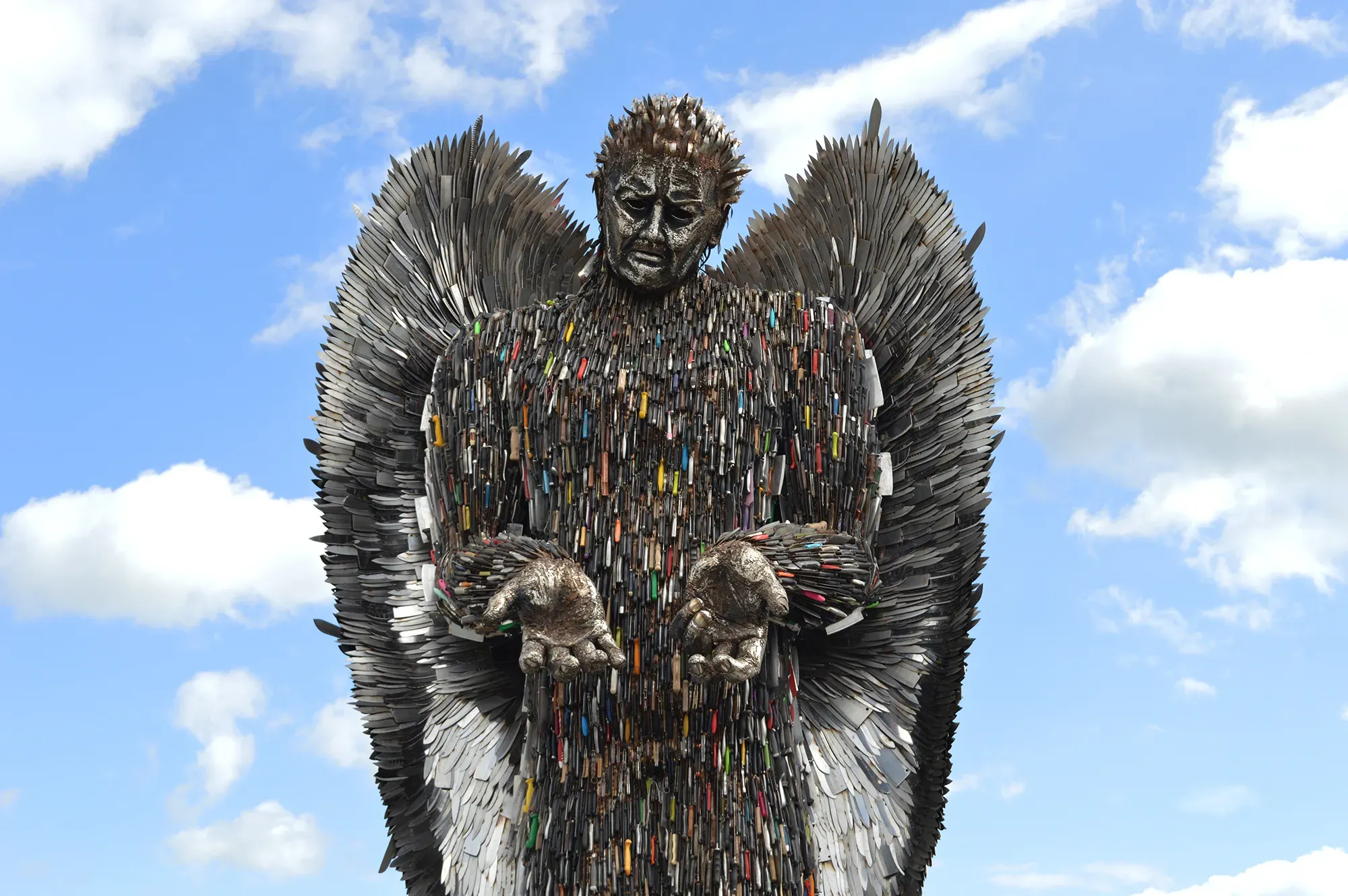 Maac There Is A Statue Of A Man With Wings Made Of Many Different Colored Objects