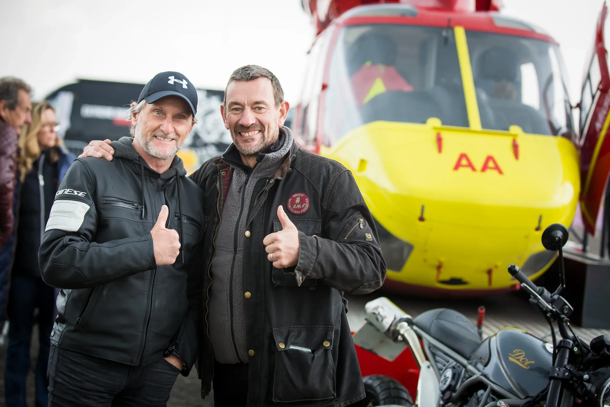Maac They Are Two Men Standing Next To Each Other In Front Of A Helicopter