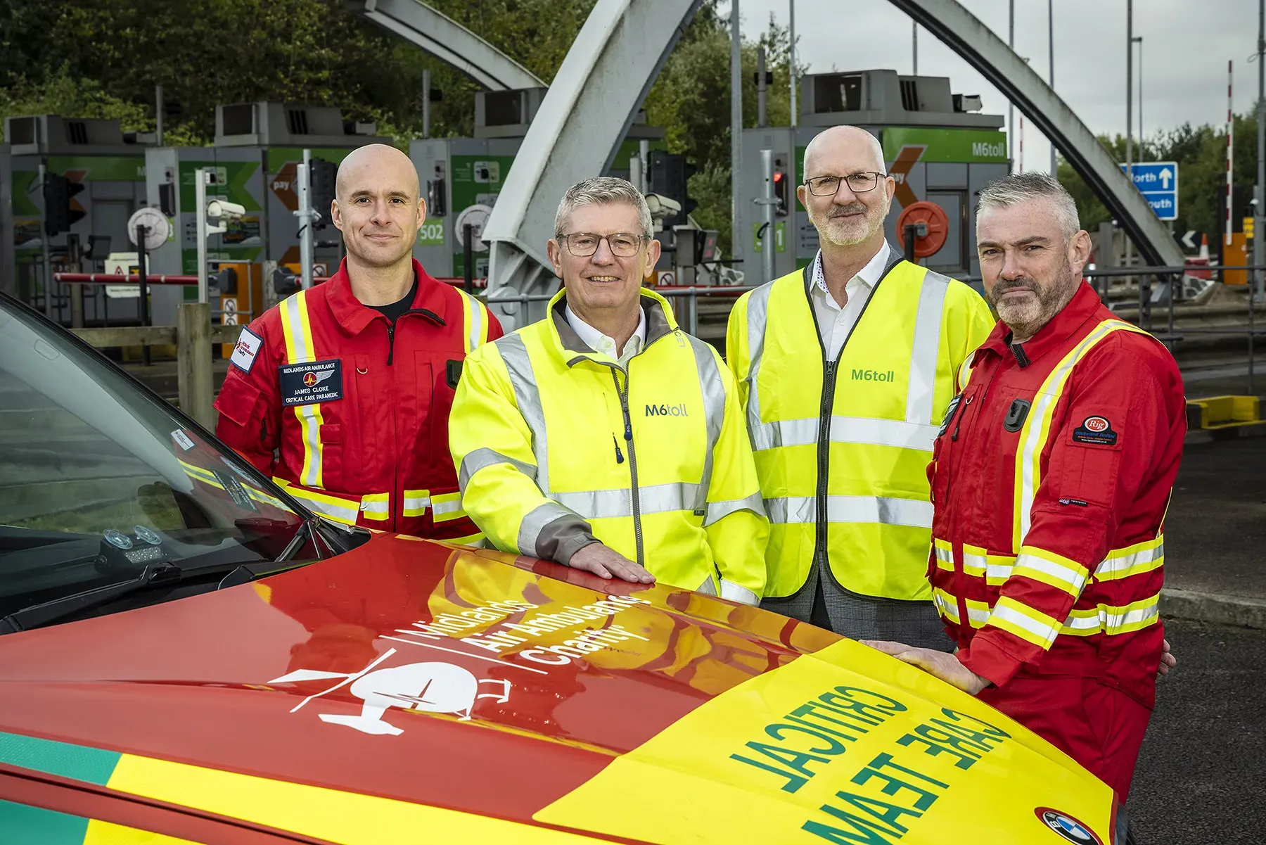 Maac Three Men In Yellow Jackets Standing Next To A Red And Yellow Car