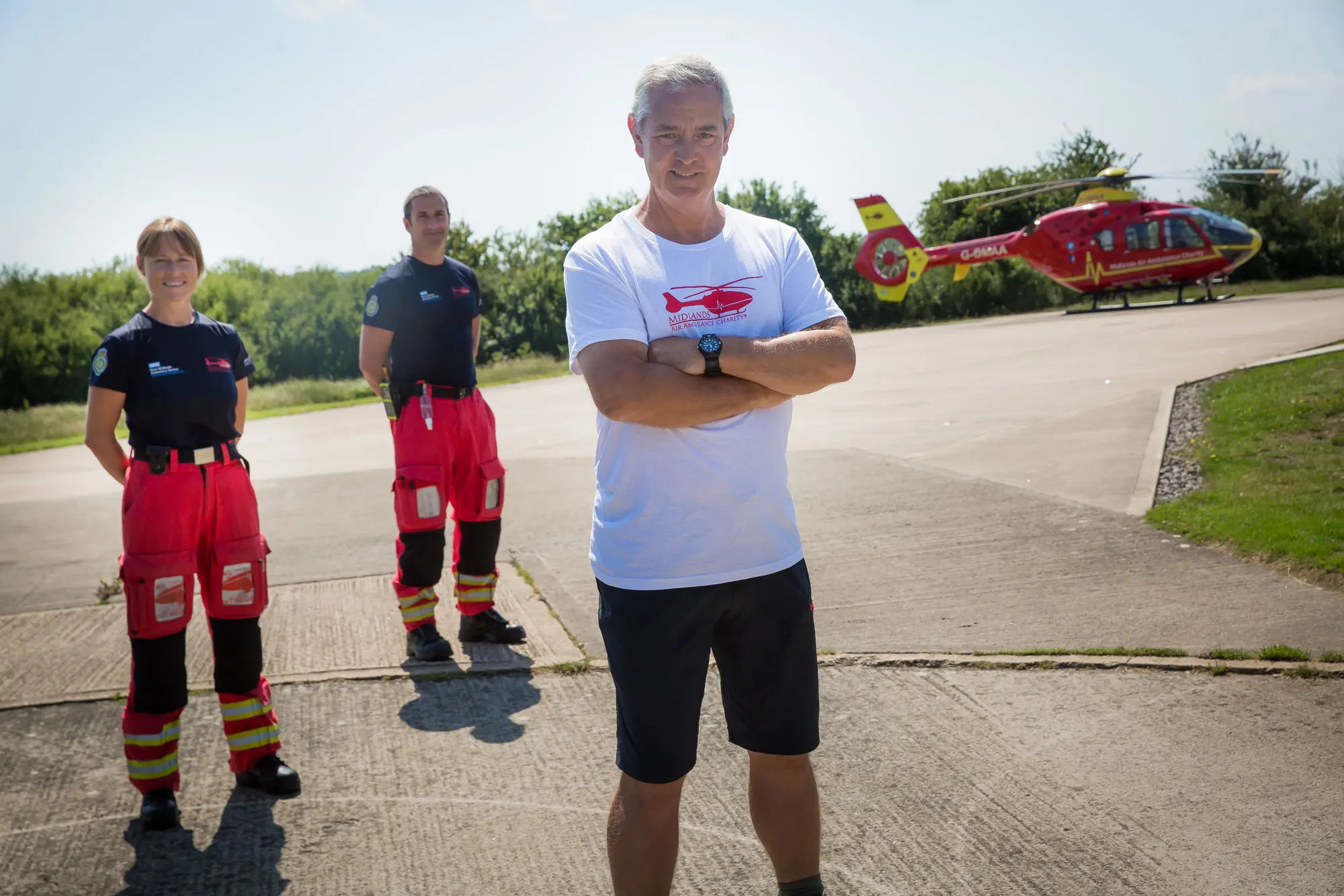 Maac Three Men Standing In Front Of A Helicopter With A Helicopter In The Background