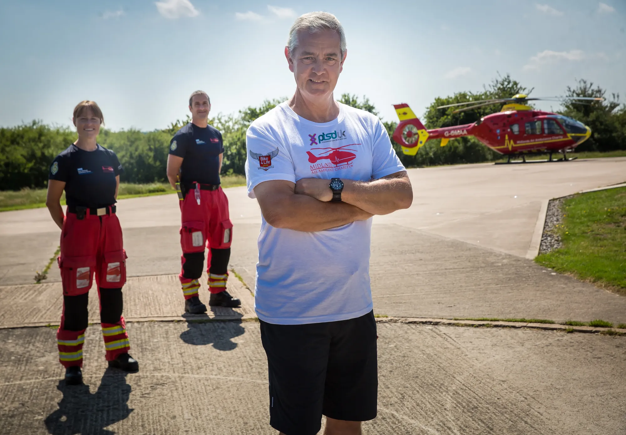 Maac Three Men Standing In Front Of A Helicopter With A Helicopter In The Background