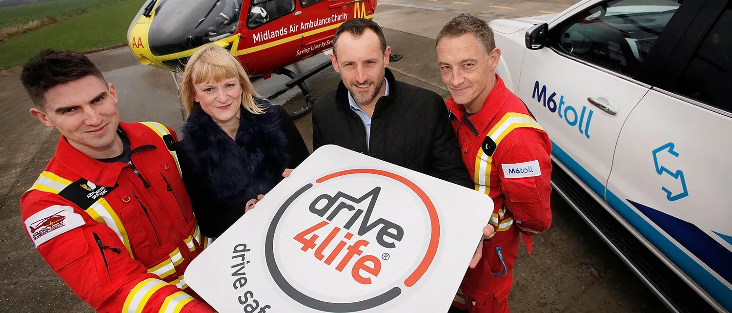 Maac Three People In Red Uniforms Holding A Sign In Front Of A Helicopter