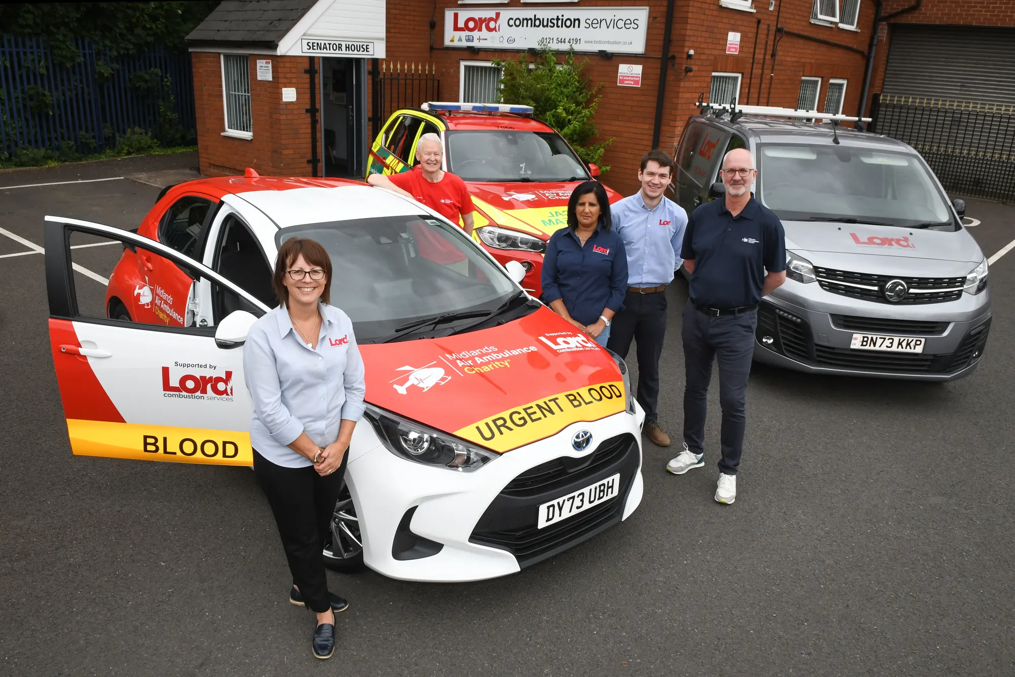 Maac Three People Standing Next To A Car With Blood Written On It