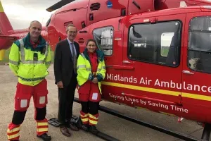 Maac Three People Standing Next To A Helicopter With A Man In A Yellow Vest