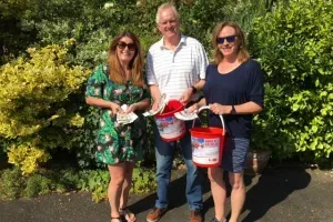 Maac Three People Standing Next To Each Other Holding Buckets Of Food