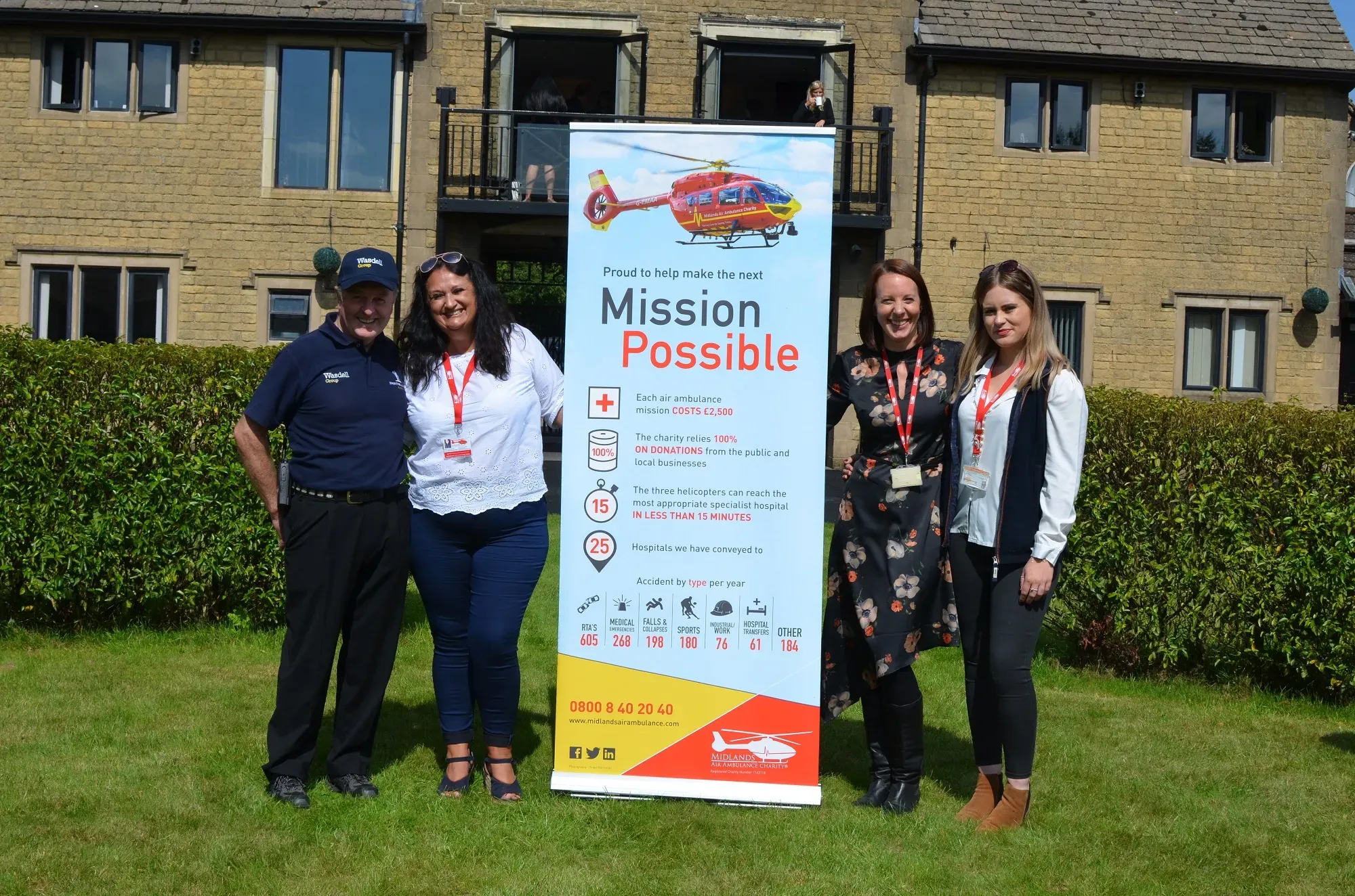 Maac Three Women And A Man Standing Next To A Sign In Front Of A Building