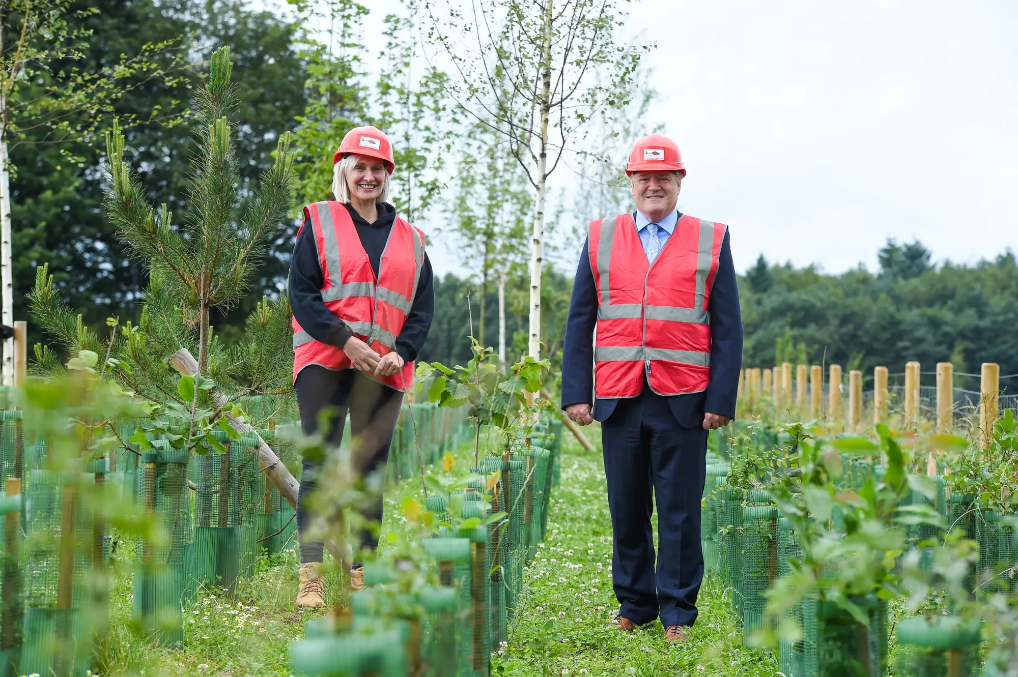 Maac Two Men In Safety Vests Standing In A Field Of Trees