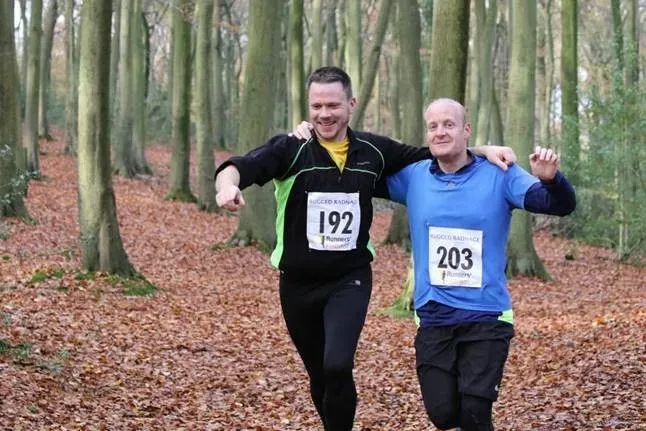 Maac Two Men Running In A Forest With Trees And Leaves