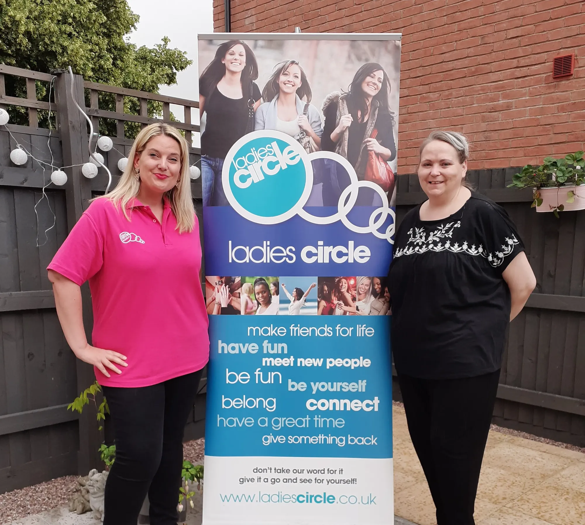 Maac Two Women Standing Next To A Sign Advertising Ladies Circle