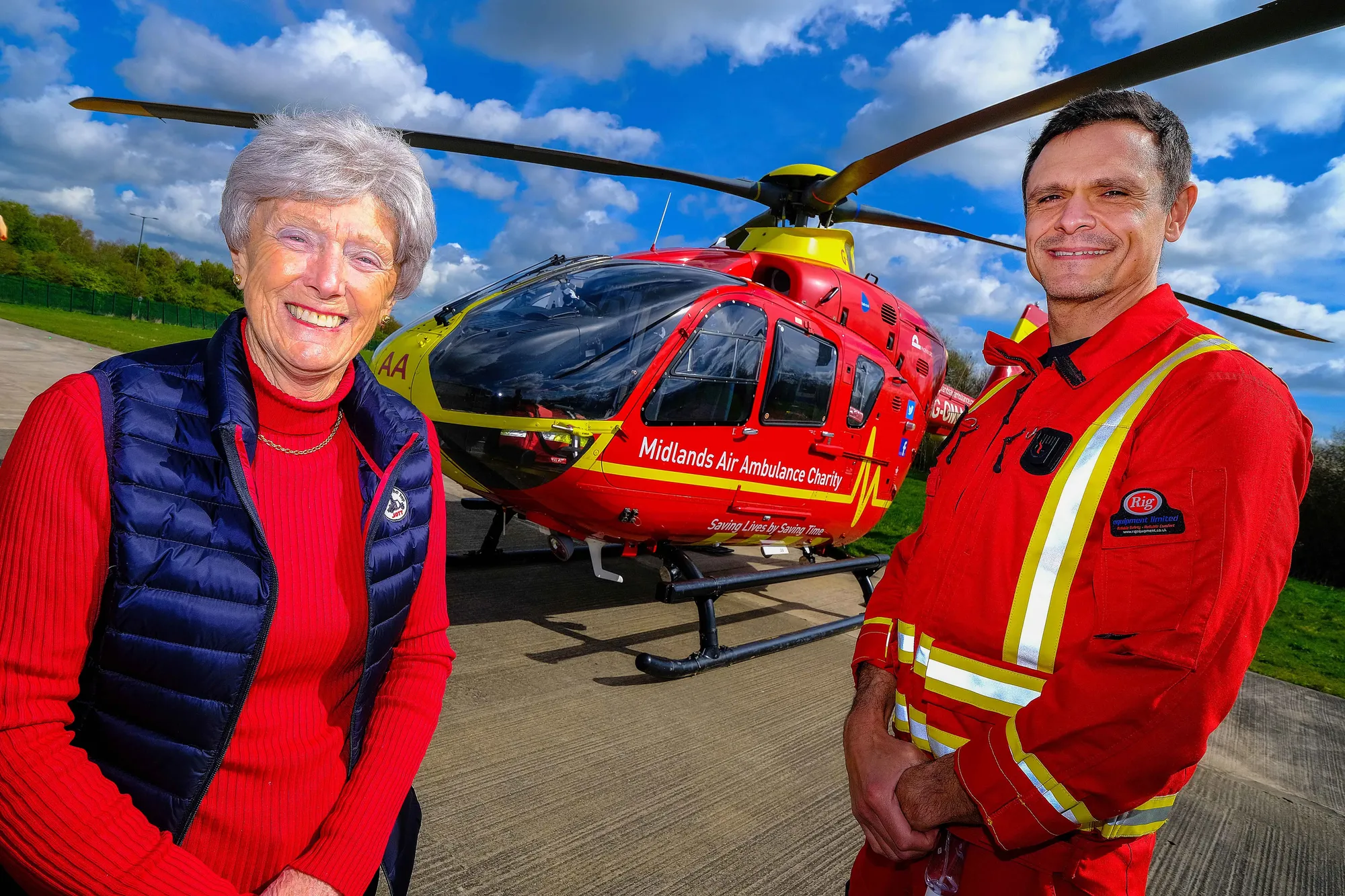 Maac Woman And Man Standing In Front Of A Helicopter