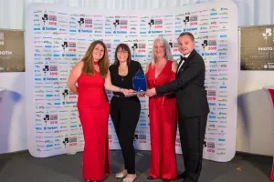 Maac Woman In Red Dress Standing Next To Two Men And A Woman In Black Dress