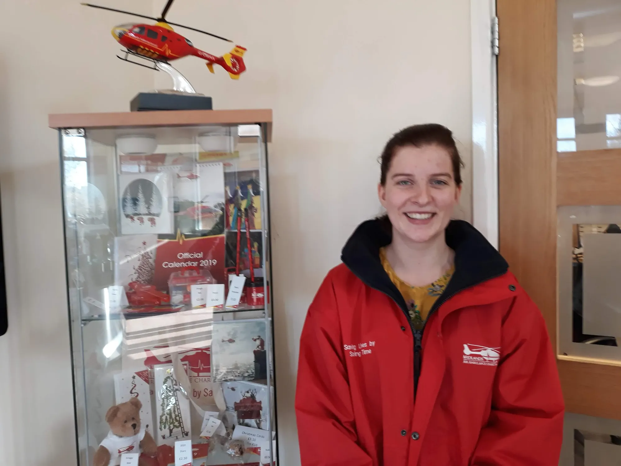 Maac Woman In Red Jacket Standing In Front Of A Display Case