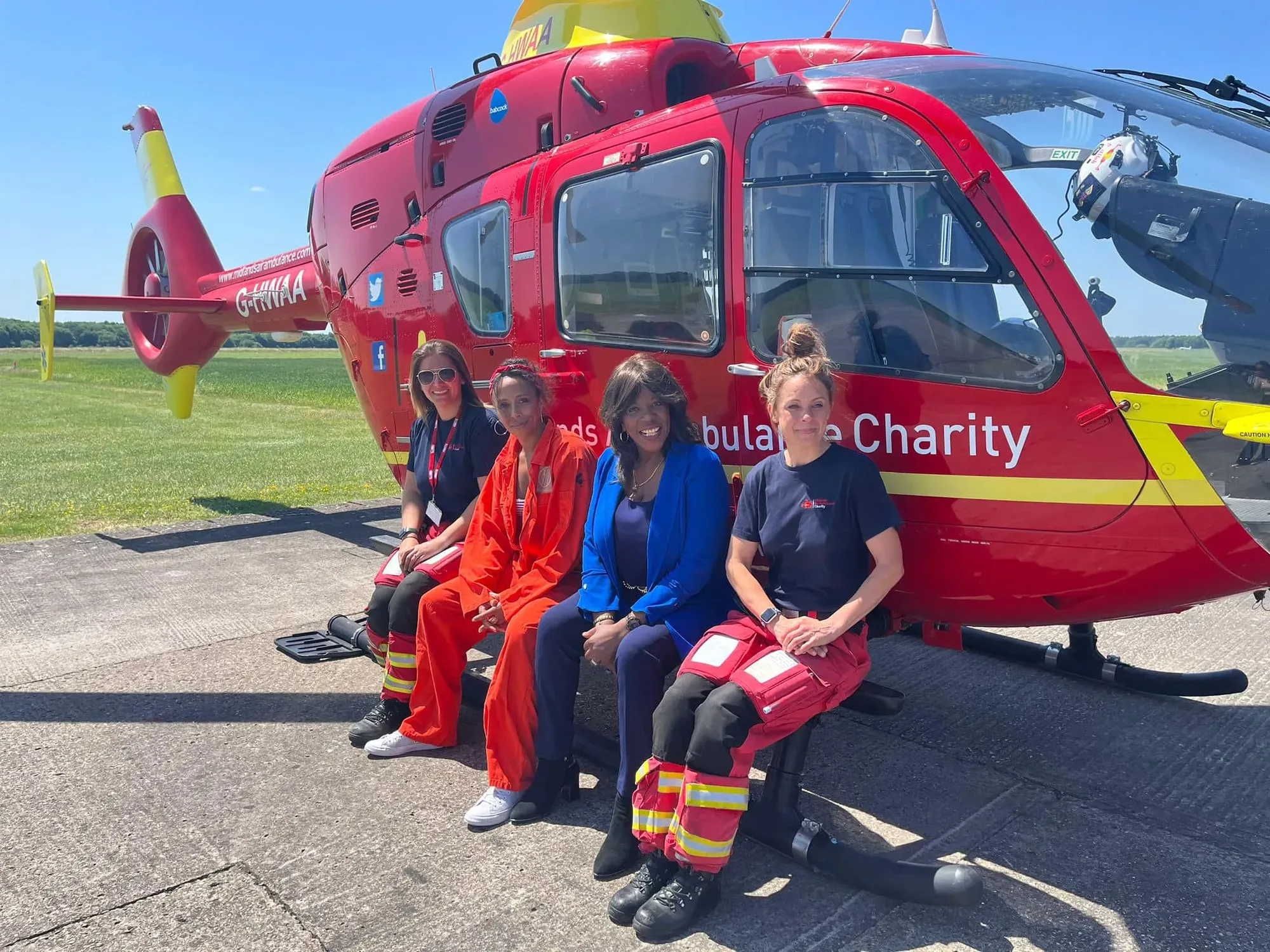 Maac Woman Sitting On A Bench Next To A Red Helicopter