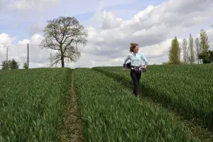 Maac Woman Walking Through A Field Of Green Grass